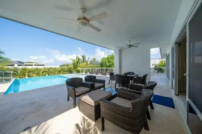 a patio with chairs and tables and a swimming pool at AC in Living Room, Infinity, Pool Luxury in Sosúa