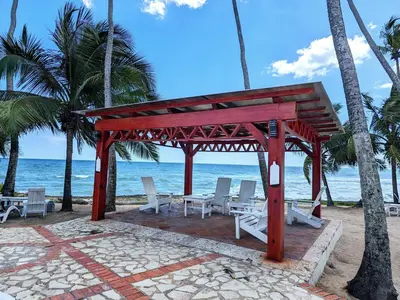 a pavilion on the beach with chairs and the ocean at Apartamento frente al mar en Albatros in Villas del Mar