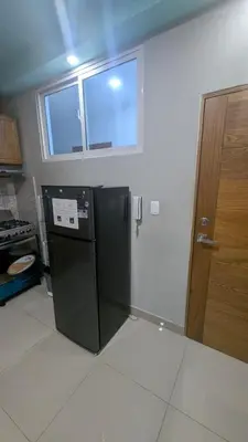 a kitchen with a black refrigerator and a window at Mitaly apartamentos RD H in Santo Domingo