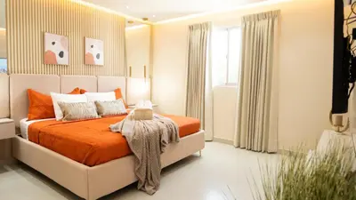 a bedroom with a bed with an orange bedspread at Luxurious PH, Near Airport,Private Jacuzzi in Santiago de los Caballeros