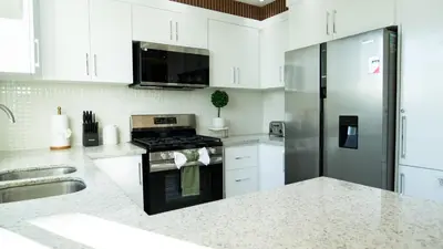 a white kitchen with a stove and a refrigerator at Luxurious PH, Near Airport,Private Jacuzzi in Santiago de los Caballeros
