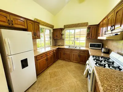 a kitchen with wooden cabinets and a white refrigerator at Residencial Hispaniola2 MastersMaidPoolBBQ in Sosúa