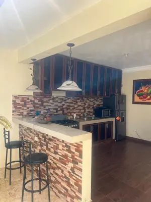 a kitchen with blue cabinets and a counter with stools at House with Pool and Calm in La Romana