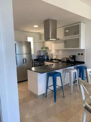 a kitchen with a large island with blue bar stools at Casual and comfort condo at Cana Rock Condos in Punta Cana