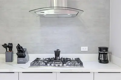 a white kitchen with a stove top with a hood at Upscale Condo, Spectacular Views in Santo Domingo