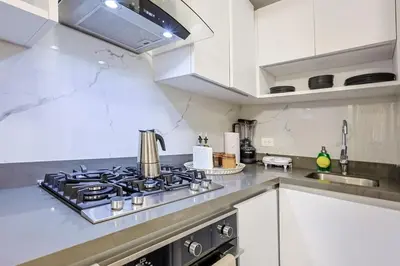 a kitchen with a stove top oven next to a sink at Comfy 1BR Apt, King Bed, Pool in Santo Domingo