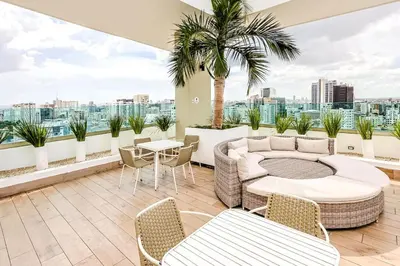 a balcony with a couch and chairs and a table at Cozy City-Center 1BD Condo, Pool in Santo Domingo