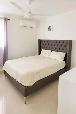 a bed in a white room with a large bed at Relax cibao airport stay in Santiago de los Caballeros