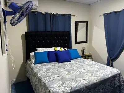a bedroom with a bed with blue curtains at Villa Del Risco - House on the Beach in Boca Chica