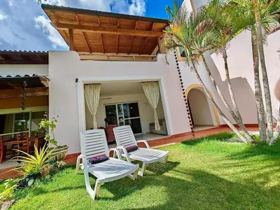 two white chairs sitting in the grass in front of a house at Apartman Tamarindo in La Laguna