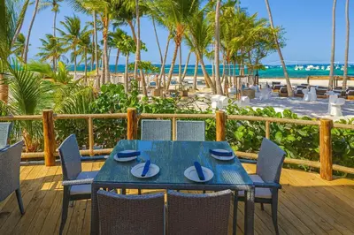 a blue table and chairs on a deck with the beach at Comfy 3BD Condo in Cocotal in Punta Cana