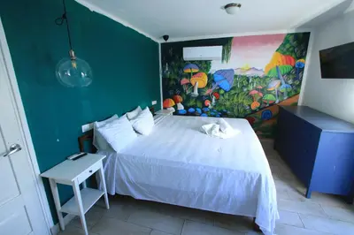 a bedroom with a white bed with a painting on the wall at Brisa de Alma Guesthouse in Bayahibe