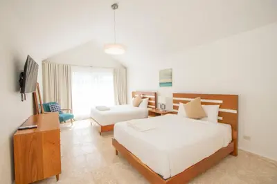 a bedroom with two beds and a desk and a television at Modern 2BR Caribbean Apt -Pool & Beach Access in Puerto Plata