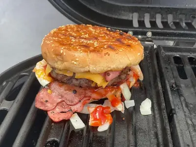 a hamburger with meat and vegetables on a grill at Beach Days & City Nights! Centrally Near Everything in Santo Domingo