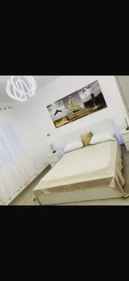 a bedroom with a white bed with posters on the wall at Jolie condo in Boca Chica