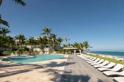 a resort pool with chaise lounge chairs and the ocean at 1BR Ocean View Luxury Beachfront in Cabarete in Cabarete