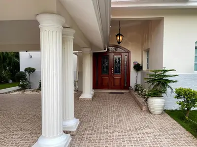 a porch with white columns and a wooden door at Villa in Metro Country Club, Juan Dolio in Juan Dolio