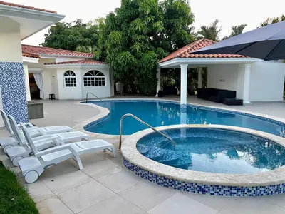 a swimming pool with two chairs and an umbrella at Villa in Metro Country Club, Juan Dolio in Juan Dolio