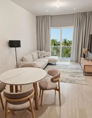 a living room with a couch and a table and chairs at Apartamento de Lujo Punta Cana Hard Rock in Punta Cana