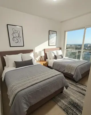 two beds in a bedroom with a large window at Apartamento de Lujo Punta Cana Hard Rock in Punta Cana