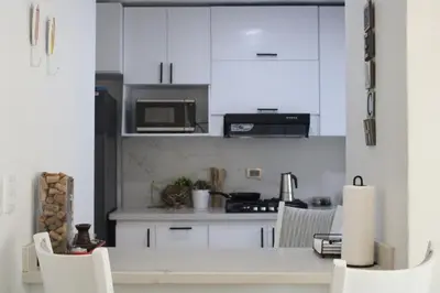 a kitchen with white cabinets and a table and chairs at Casa Bonita con Jacuzzi in Los Mameyes