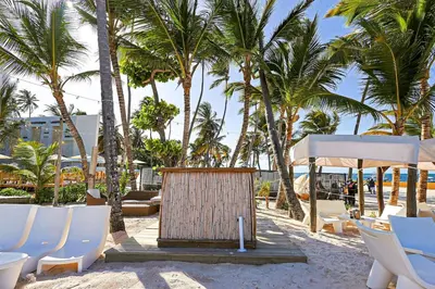 a beach with white chairs and palm trees at Elegant Cocotal 2BD Condo in Punta Cana
