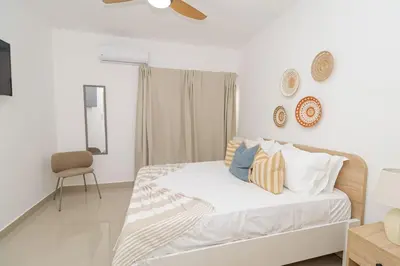 a white bedroom with a bed and a chair at Sylish 2 Bed Retreat in Sunshine Bayahibe in San Rafael del Yuma