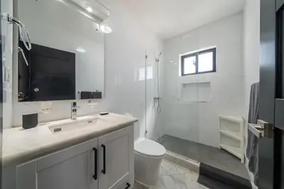 a white bathroom with a toilet and a shower at Brand New Modern Caribbean Retreat 3BR in Sosúa