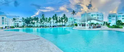 a swimming pool in a resort with palm trees and buildings at Residencial la ensenada, on Playa Nueva Romana