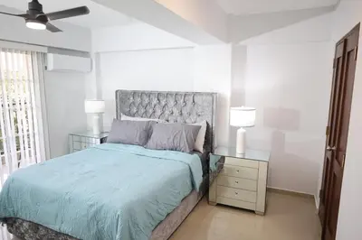 a bedroom with a bed with a blue comforter and two lamps at Emerald Vue - Private river entrance in Jarabacoa