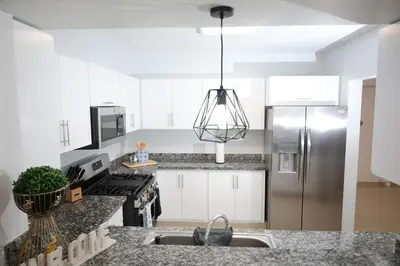 a kitchen with white cabinets and a stainless steel refrigerator at Emerald Vue - Private river entrance in Jarabacoa