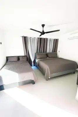 two beds in a room with a ceiling fan at Penthouse with Large Rooftop Terrace & Parking in Sosúa
