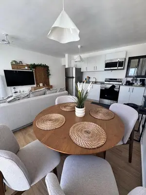 a kitchen and living room with a wooden table and chairs at Cozy Apt Steps from Los Corales Beach in Punta Cana