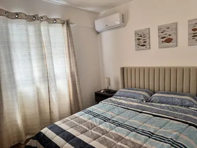 a bedroom with a bed with a blanket and a window at Cozy Apt Steps from Los Corales Beach in Punta Cana
