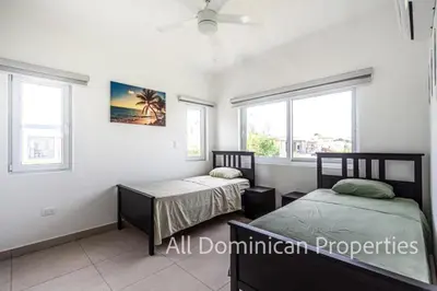 two beds in a room with two windows at Sosua Ocean Village, Villas 24 in Sosúa
