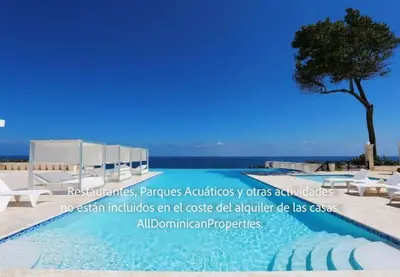 a swimming pool with white chairs and a tree at Sosua Ocean Village, Villas 24 in Sosúa