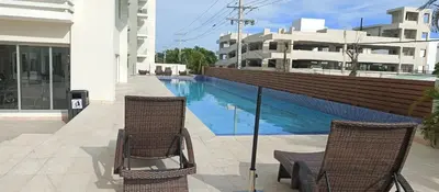 a pair of chairs sitting next to a swimming pool at Boca del Mar Tower III Apart 401 in Boca Chica