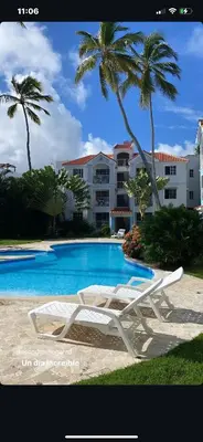 a white lounge chair sitting next to a swimming pool at Vista del Sol Pool and Beach los Corales Rd in Punta Cana