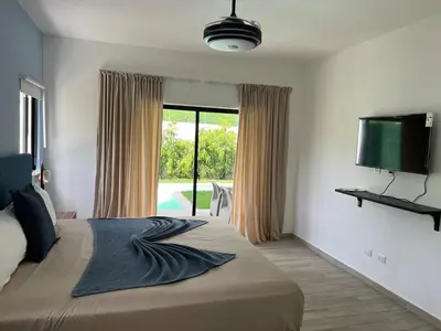 a bedroom with a large bed and a flat screen tv at Swim up and Beach Getaway at White Sands in Punta Cana