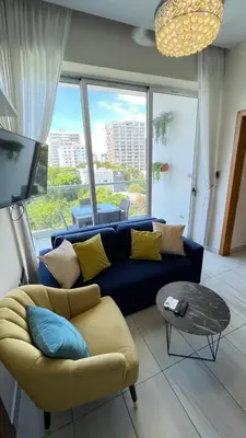 a living room with a blue couch and a large window at Lujoso apartamento en Piantini in Santo Domingo
