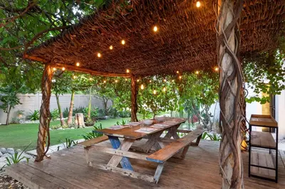 a wooden picnic table under a wooden pergola at Bayshore 76 Beachfront Villa Palmar de ocoa in Palmar de Ocoa