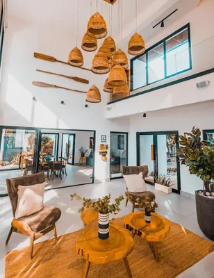 a living room with chairs and tables and windows at Bayshore 76 Beachfront Villa Palmar de ocoa in Palmar de Ocoa