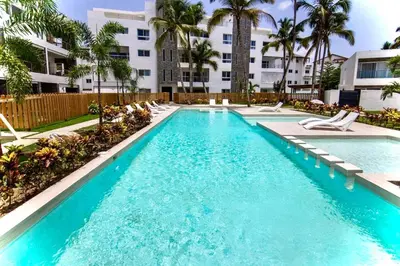a swimming pool with chairs and a building at Modern apartament near the sea-Las Terrenas in Las Terrenas