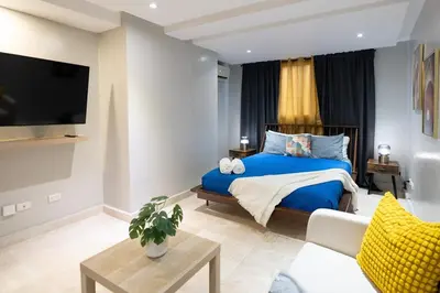 a bedroom with a blue bed and a tv at City Center, 2-BR Suite close to Shops, Restaurants, Bars and More in Santo Domingo