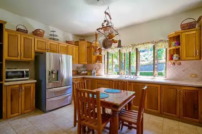 a kitchen with a table and a refrigerator at ®4BR{Wood~Mountain~Villa} @Jarabacoa Heated Pool in Jarabacoa