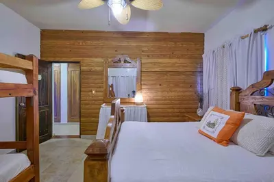 a bedroom with a bed and a table in it at ®4BR{Wood~Mountain~Villa} @Jarabacoa Heated Pool in Jarabacoa