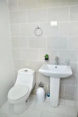 a white bathroom with a toilet and a sink at Luxury Pool Gym Basketball in Santiago de los Caballeros