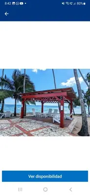 a picture of a red bench on the beach at Atardecer Albatros in Juan Dolio