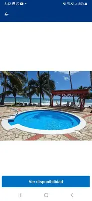 a screenshot of a website with a picture of a swimming pool at Atardecer Albatros in Juan Dolio