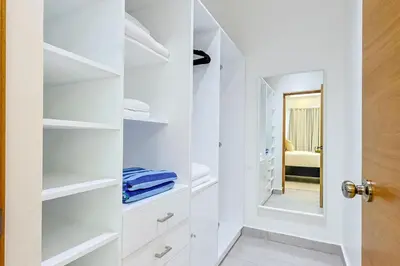 a bathroom with white shelves and a mirror at Cozy 1BR Condo, Pool, Gym in Santo Domingo
